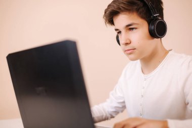 Genç çocuk odasında dizüstü bilgisayarında oyun oynuyor. Buharlı gemi kablosuz kulaklık kullanıyor. Mutlu oyuncular bütün gün oynar.