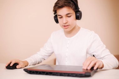 Kablosuz kulaklıklı çocuk dizüstünü aç ve oyun oynamaya başla. Yakışıklı genç vapur.