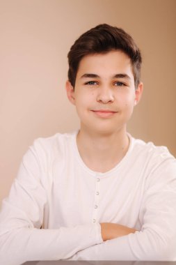 Beyaz kazaklı, gülümseyen bir gencin portresi. Oyun oynadıktan sonra hippi yakışıklı çocuk