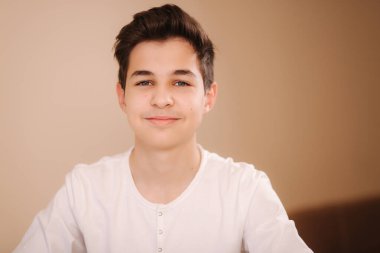 Beyaz kazaklı, gülümseyen bir gencin portresi. Oyun oynadıktan sonra hippi yakışıklı çocuk