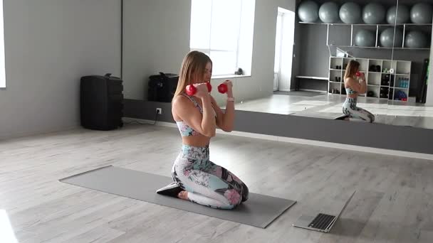 Mujer atlética en ropa deportiva hace ejercicios en casa. Mujer buscar en la tableta, mientras que los ejercicios diong. Concepto de deporte y recreación. Estilo de vida saludable — Vídeo de stock