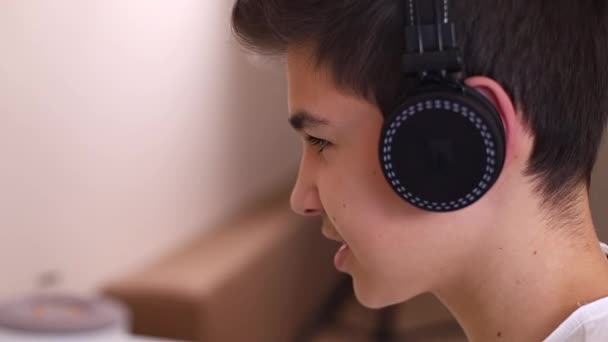 Close-up van jonge tiener jongen in draadloze hoofdtelefoon spreken met vrienden tijdens het spelen spel — Stockvideo