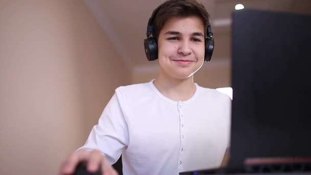 Έφηβος παίζει παιχνίδι στο λάπτοπ στο δωμάτιό του. Το ατμόπλοιο χρησιμοποιεί ασύρματα ακουστικά. Χαρούμενο παιχνίδι όλη μέρα. — Αρχείο Βίντεο