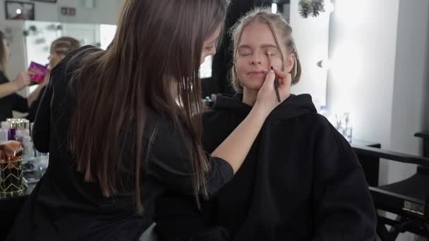 Woman make makeup for attractive blond hair woman in studio. Video of makeup artist applying cosmetics for beautiful model — Stock Video