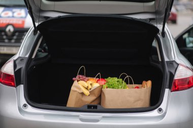 Araba bagajındaki süpermarketten aldıklarım. Karantina sırasında yemek teslimatı. Alışveriş için kağıt eko poşetler. Taze meyve ve sebze, vejetaryen.