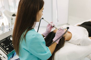 Yumuşak tenli bir kadın yüzü. Kozmetoloji kliniğindeki kadın cilde yapışmak için güzellik prosedürü uyguluyor.