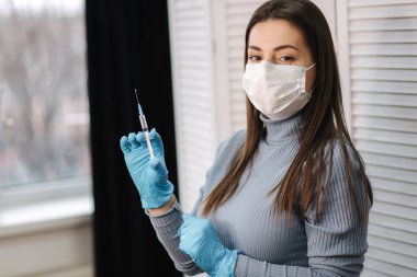 Covid-19 Corona virüsüne karşı kavramsal mücadele. Kadın elinde sıvı aşılarla bir şırınga tutuyor.