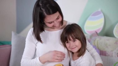 Küçük kız ve annesi evde köpekle oynuyorlar. Mutlu aile Paskalya için hazırlanıyor. Çekici genç anne küçük kızını ve köpeğini seviyor.