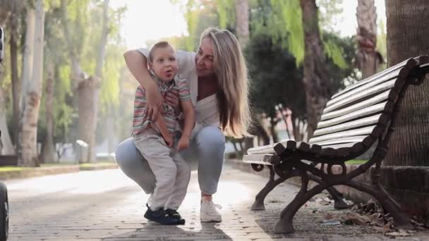 Šťastná máma si hraje se svým synem, když jdou ven. Kluk s fyzickou slabostí. Video vychutnat šťastnou lásku rodiny venku. Šťastné chvíle. Koncept péče o postižené — Stock video