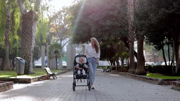 Видео, на котором мать семьи выходит на улицу и ухаживает за ребенком-инвалидом, сидящим в инвалидных колясках. Концепция ухода за инвалидами — стоковое видео