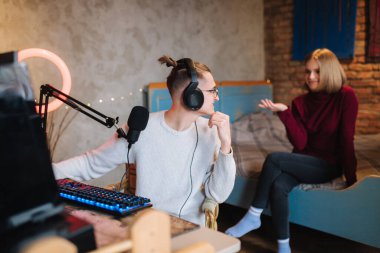 Güzel sarışın kız arkadaşı yatakta oturur ve bilgisayarla çalışan erkek arkadaşının üzerine oturur. Adam kızdan ipuçları ister.