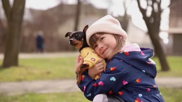 Bella passeggiata bambina con cane carino all'aperto. Sei anni ragazza abbracciare il suo animale domestico — Video Stock