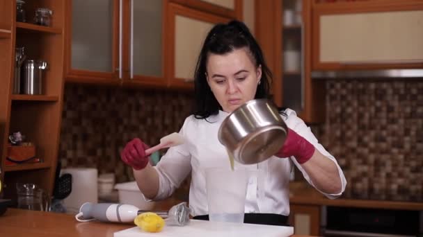 Η γυναίκα φτιάχνει κρέμα για κέικ. Διαδικασία παρασκευής παραδοσιακής σπιτικής τούρτας στο σπίτι. Κοντινό πλάνο της γυναίκας χύνει σε ένα άλλο μπολ — Αρχείο Βίντεο