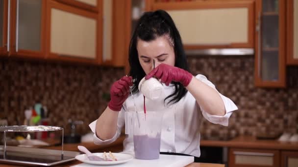 Kvinna blandar mat färg för grädde. Professionell konfektyr med rött färgämne i köket — Stockvideo