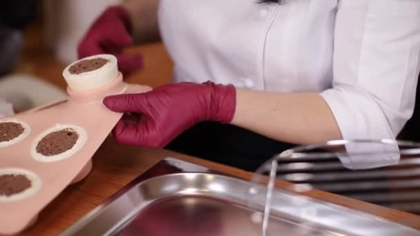 Frau in rosa Handschuhen nimmt gefrorenen Nachtisch aus Silikonformen und stellt ihn auf — Stockvideo