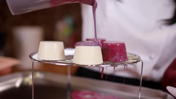 Випічка шеф-кухаря п'є дзеркальне глазурування на торт. Червона глазур тече вниз по підставці. Професійний кондитер, що працює на кухні — стокове відео