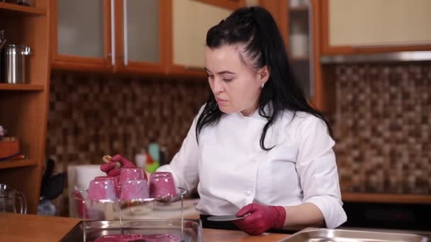 Kvinnlig konditor i vit kittel dekorerad dessert på kök — Stockvideo