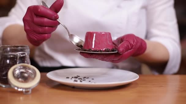 Konditorin in weißem Kittel dekoriert leckeres Dessert in der Küche. Nahaufnahme der Hände in rosa Handschuhen halten Süße und Arbeit — Stockvideo