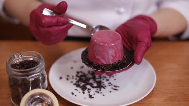 Kvinnlig konditor i vit kittel dekorerad välsmakande dessert på kök. Närbild av händer i rosa handskar hålla sötma och arbete — Stockvideo