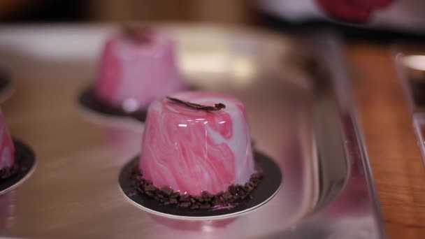 Konditorin in weißem Kittel dekoriert leckeres Dessert in der Küche. Nahaufnahme der Hände in rosa Handschuhen halten Süße und Arbeit — Stockvideo