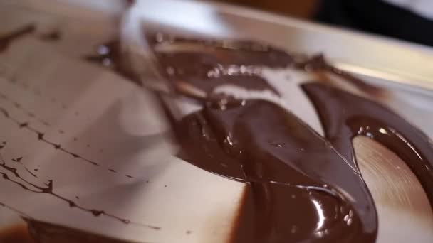 Confectioner is working with melted chocolate using putty knife. Woman in pink gloves making sweet base for cake. Closeup mixes milk chocolate — Stock Video