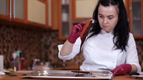 Professionell kvinnlig konditor gör chokladtårta. Kvinnan lagar mat i köket. Framställning av mjölkchoklad hemma. Matlagning, bakning koncept — Stockvideo