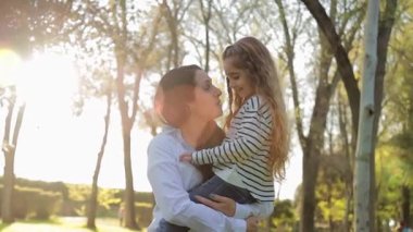 Genç anne parkta küçük kızına sarılıyor. Mutlu aile