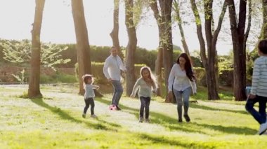 Çocuklarla aktif yürüyüş. Anne ve babanın mutlu aileleri dışarıda çocuklarla vakit geçiriyor. Genç anne ve babasıyla ağaç çocukları koşup zıplıyorlar.