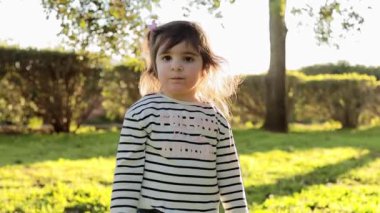 Gün batımında parkta yürüyen küçük bir kız. Mutlu kadın çocuk gülümsemesi