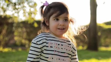 Gün batımında parkta yürüyen küçük bir kız. Mutlu kadın çocuk gülümsemesi
