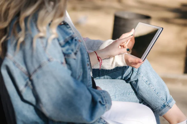 Gravid kvinna med sin bästa vän sitter i parken och letar efter barnvagn med hjälp av tablett. Två kvinnor i solglasögon väljer kläder till barnet — Stockfoto