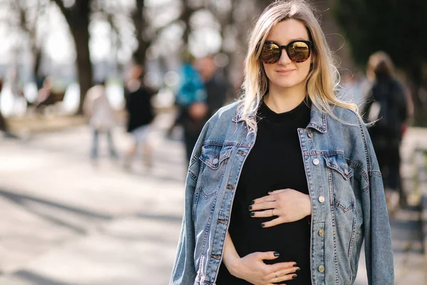 Mujer embarazada joven caminando al aire libre durante la cuarentena. Atractiva futura madre en gafas de sol pasó tiempo al aire libre — Foto de Stock