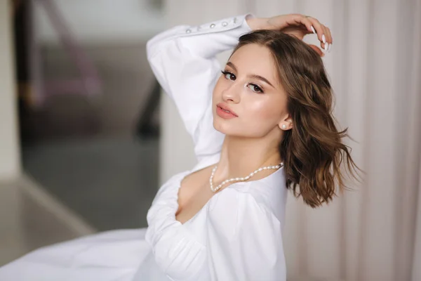 Portret młodej i eleganckiej kobiety w białej sukience z pięknym makijażem i fryzurą. wspaniały model pozowanie do fotografa w studio — Zdjęcie stockowe