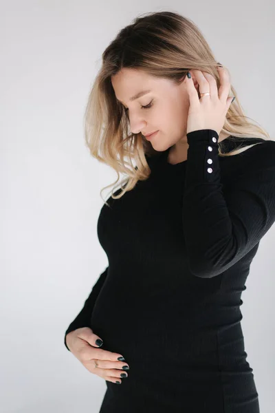 Retrato de mulher grávida em estúdio sobre fundo branco. Bela futura mãe colocou as mãos na barriga. Cabelo solto — Fotografia de Stock