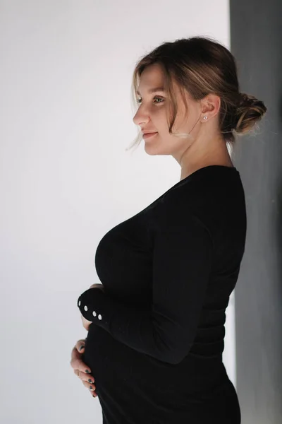 Primer plano retrato de la mujer embarazada en el estudio sobre fondo blanco. Hermosa futura madre puso sus manos en su vientre —  Fotos de Stock