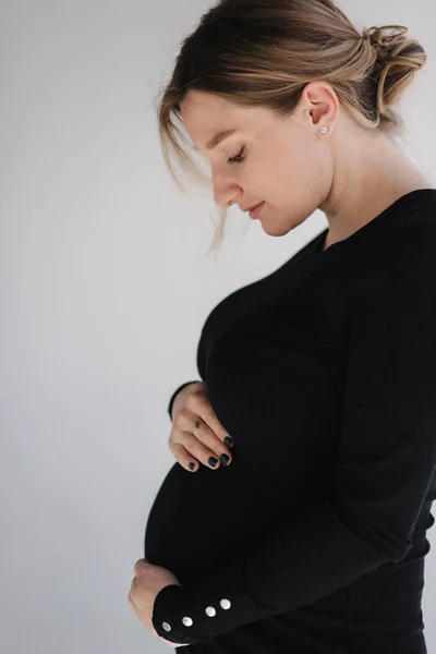 Primer plano retrato de la mujer embarazada en el estudio sobre fondo blanco. Hermosa futura madre puso sus manos en su vientre —  Fotos de Stock