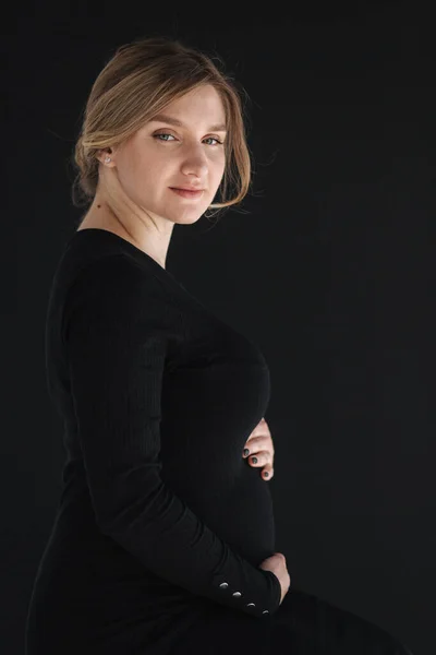 Крупным планом портрет голодной беременной женщины в бакалейном платье держит руку на животе и смотрит вниз — стоковое фото