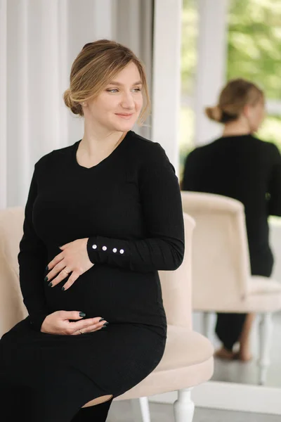 Hermosa mujer embarazada sentada en la silla en casa. Mujer esperando al bebé — Foto de Stock