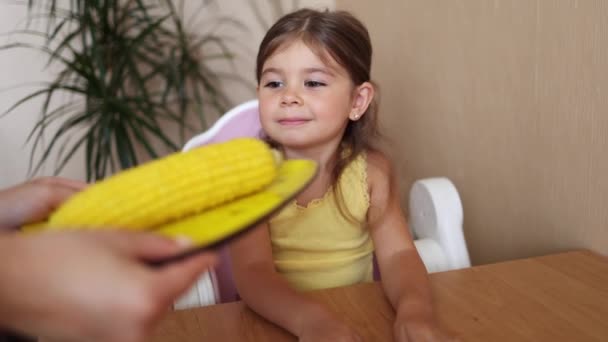 Szczęśliwa dziewczynka czeka na kukurydzę. Mama przynosi świeżo ugotowaną kukurydzę dla swojej uroczej córki — Wideo stockowe