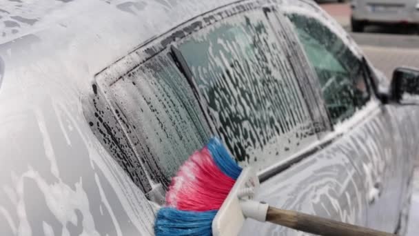 Primo piano di femminile che lava l'auto con shampoo e spazzole. Auto lavaggio all'aperto. Lather corre giu 'dal retro dell'auto. Rallentatore — Video Stock