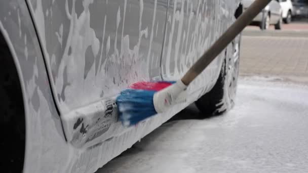 Primo piano di femminile che lava l'auto con shampoo e spazzole. Auto lavaggio all'aperto. Lather corre giu 'dal retro dell'auto. Rallentatore — Video Stock