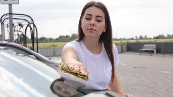 Attraente felice gioioso conducente femminile pulire parabrezza sulla sua auto utilizzando straccio in self-service car wash — Video Stock