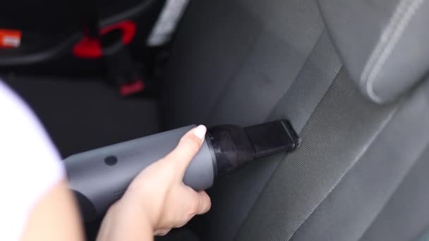 Close-up perempuan menggunakan vacuum cleaner portabel di mobilnya. Pembersihan interior mobil. Wanita menyedot kursi. Debu dan tanah penghapusan — Stok Video