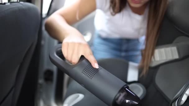 Uma mulher a aspirar o carro na garagem em casa. Feminino usando aspirador portátil para remover poeira e sujeira. Limpeza interior do carro — Vídeo de Stock