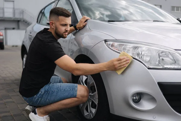 Adamın eli arabasının farlarını halıyla siliyor. self-servis araba yıkama. Açık hava. — Stok fotoğraf