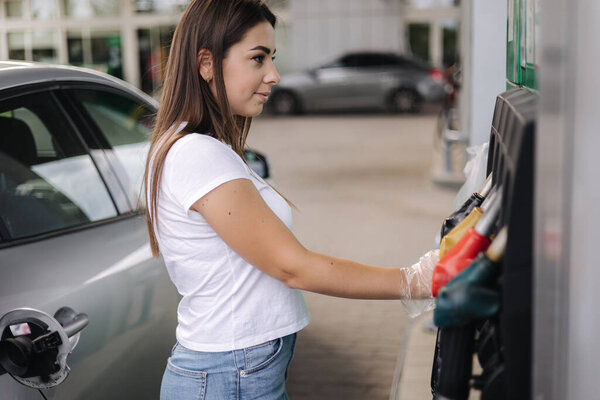 Woman is preparing for refueling at gas station. Female hand filling benzine gasoline fuel in car. Petrol prices concept