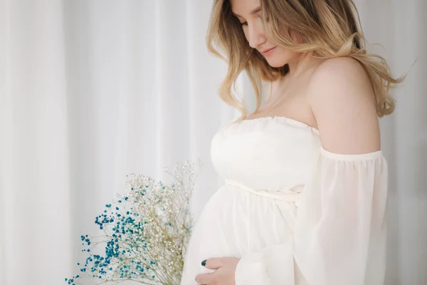 Retrato de cerca de la mujer embarazada en vestido blanco puso su mano en el vientre y esperando para que el bebé se mueva —  Fotos de Stock