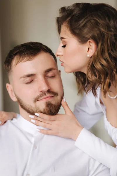 Portrait of young woman kiss husband. Attractive female with her lovely man. White clothes — Stockfoto