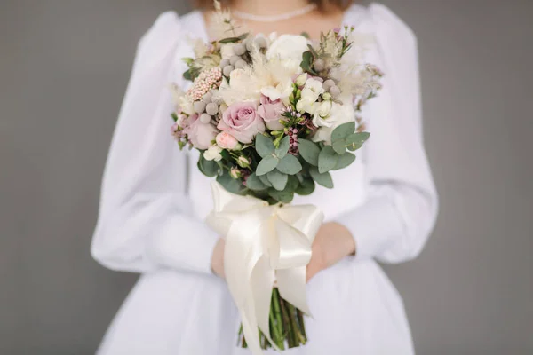 Middle selection of bride hold wedding bouquet in hands. Grey background. Stuio photosession — Stock fotografie