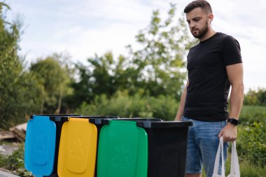 Çöpler için ekolojik paketi olan bir adam çöpleri geri dönüşüm kutularına taşır. Geri dönüşüm kavramı